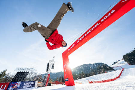 On January 17th, 2026, Jason Paul performs a flip at the finish line of the Streif in Kitzbühel, Austria, set against a mountain backdrop.
