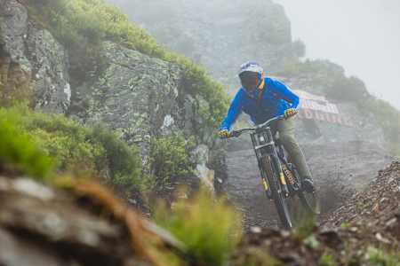 Im Jahr 2025 fährt Matt Jones durch einen schlammigen Abschnitt der Red Bull Hardline-Strecke im nebligen Dyfi Valley in Wales.