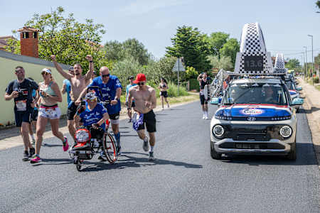 Läufer:innen und Rollstuhlsportler:innen beim Wings for Life World Run Flagship Run in Zadar, Kroatien, im Mai 2025 dicht gefolgt vom Catcher Car.