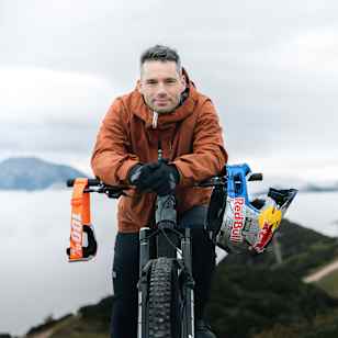 Red Bull athlete Tomáš Slavík rests with his iconic helmet and bike at Feuerkogel, Austria in 2025, ready for high-adrenaline mountain biking against a dramatic alpine backdrop