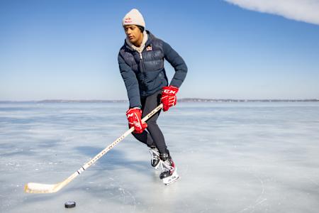 Die Iishockeyspielerin Laila Edwards schlittschuht uf em zuegfrorene See i Wisconsin und spielt mit em Puck.