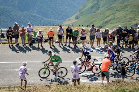 Wout van Aert mène le peloton vêtu du maillot vert, acclamé par la foule sur les pentes d’un col du Tour de France.