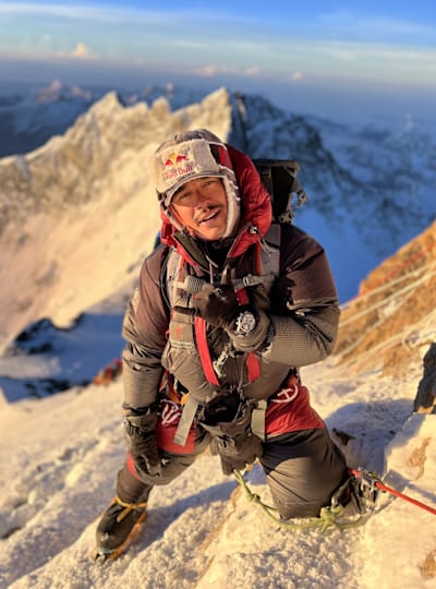 Nepali mountaineer and 14 Peaks star Nirmal 'Nims' Purja poses for a photo during the a climb with a mountain range in the background.