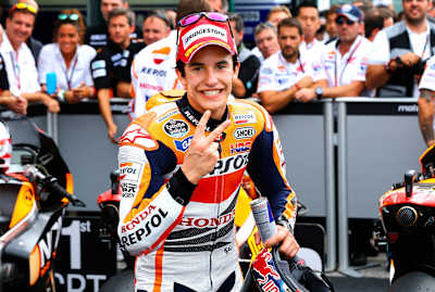 Marc Márquez, with a crowd behind him, poses for the camera on a racetrack.