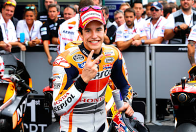 Marc Márquez, with a crowd behind him, poses for the camera on a racetrack.