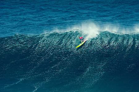 Paige Alms takes the drop while surfing at Jaws on Maui.