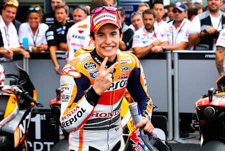 Marc Márquez, with a crowd behind him, poses for the camera on a racetrack.