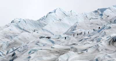 People in line walk across glacier in Argentina.