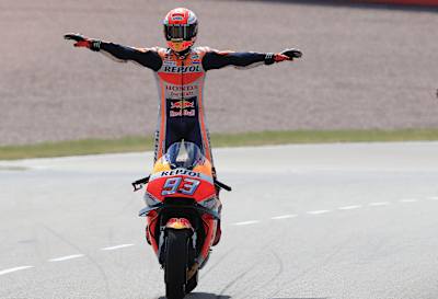 Una foto de Marc Márquez de pie sobre su moto en movimiento después de ganar el MotoGP alemán de 2018.