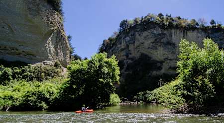A man in a canoe paddles on the Rangitikei River in New Zealand.