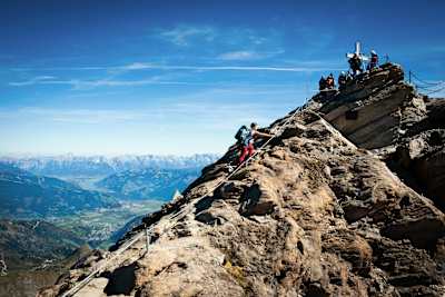 Person scrambles up route to top of mountain in Zell am See.