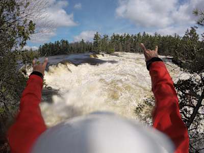 Benny Marr raises his arms in celebration at a rough river.