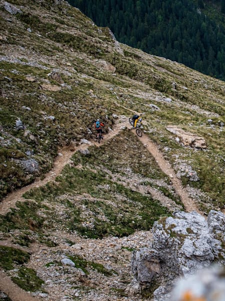 Two mountain bikers riding a switchbacked trail in Sud Tirol