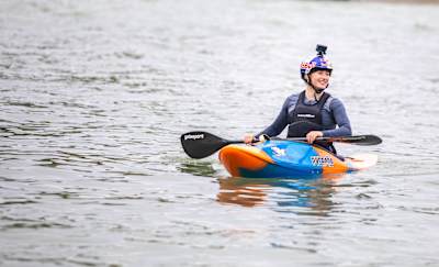Evy Leibfarth in canoe, wearing Red Bull helmet, paddling on water