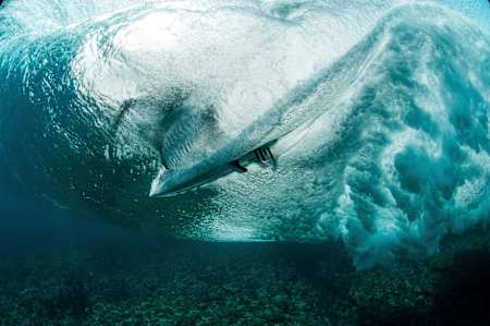 A surfer is photographed from underwater at Teahupo'o, Tahiti