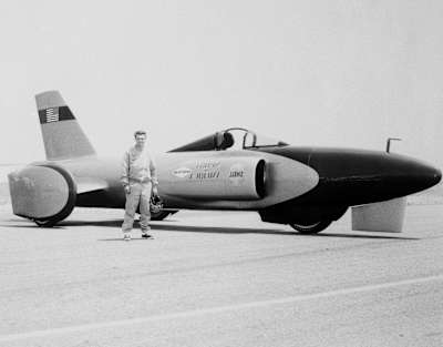A photo of Craig Breedlove standing by his three-wheeled car Spirit Of America at Bonneville Salt Flats in Utah before his land speed record attempt.