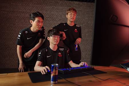 An image of T1's League of Legends esports team member Faker playing at a computer with his team-mates.