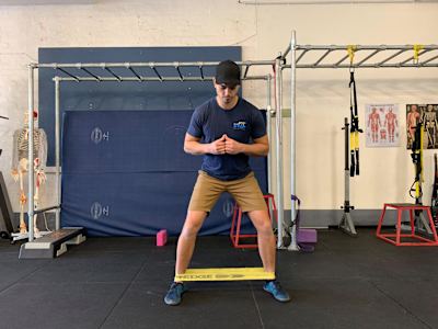 An image of a man in a gym doing stretching exercises. 