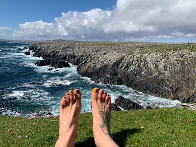 Anna McNuff shows off her feet beside a coastal cliff in Great Britain.