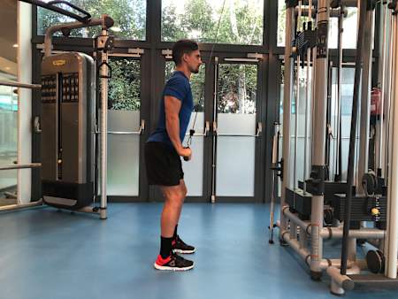 Un atlet face extensii pentru triceps la scripete în sala de sport.