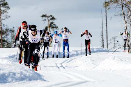 Verschillende skiërs skiën samen doorheen een besneeuwd berglandschap.