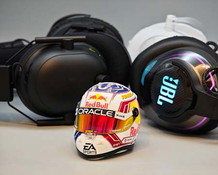 Bild zeigt eine Auswahl aktueller Gaming-Headsets von JBL, Razer, Logitech und HyperX mit einem Miniatur-Formel-1-Helm von Max Verstappen im Vordergrund.