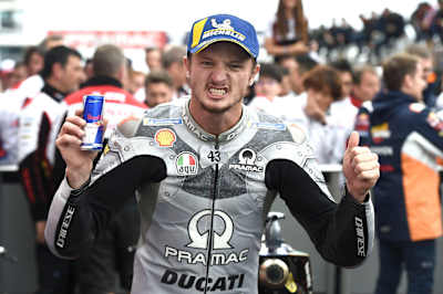 Jack Miller raises his arms in celebration and holds a can of Red Bull.