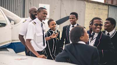 An instructor from the iFly Academy, South Africa's first black-owned aviation school, shows school students around a small plane.