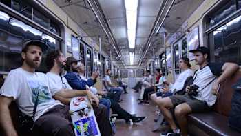 A group of skateboarders ride a subway train.