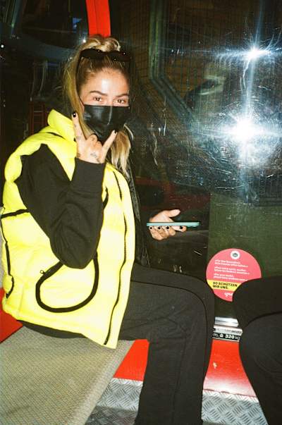 Loredana mit Maske sitzt in einer Berggondel.