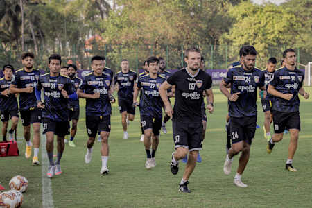 Sports scientist Csaba Gabris and players of Chennaiyin Football Club warm up during a training session.