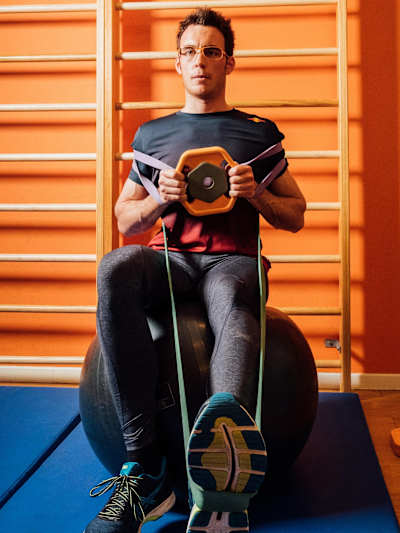 While balancing on an exercise ball, Thierry Neuville bends and stretches his left leg, holds a weight at steering height and turns it like a steering wheel.