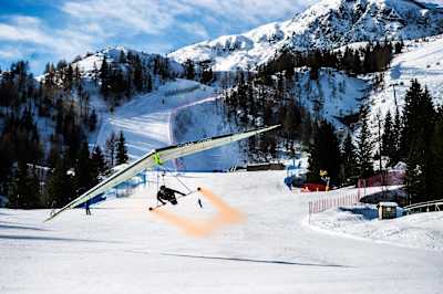 Wolfgang Siess performing a speedrun over a ski slope with his hang glider