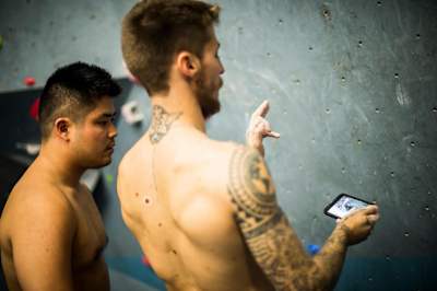 Felipe Camargo mira un movimiento en su móvil mientras entrena en un gimnasio de escalada en São Paulo, Brasil.
