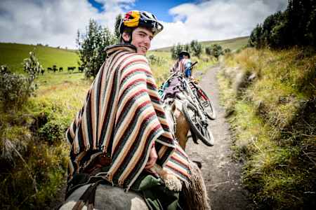 Mountain biker Finn Iles travels on the back of a horse in Quilindaña during filming of the series Rob Warner's Wild Rides in Ecuador.