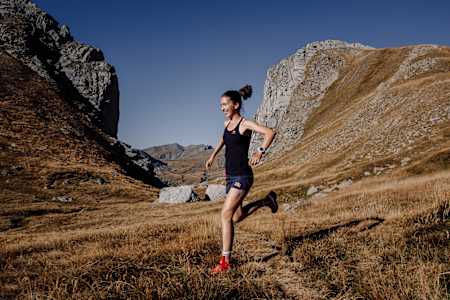 woman downhill running a mountain with a smile on her face