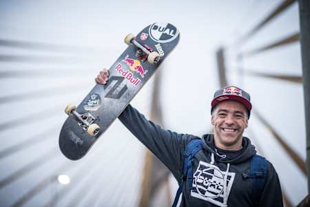 Sandro Dias holds up his skateboard. 