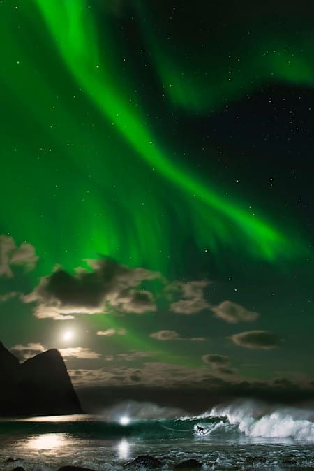 Surfer Mick Fanning surfer under nordlyset i Lofoten, Norge.