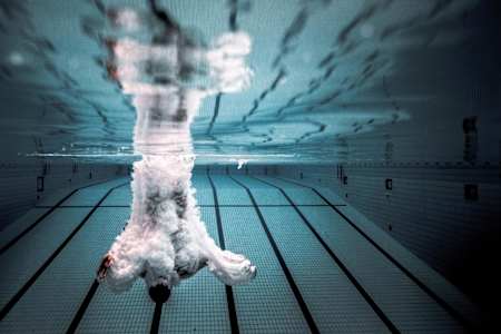 A cliff diver enters the water at high speed during a training dive.