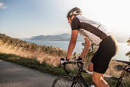 A bike rider goes up a climb standing on his pedals.
