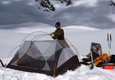 Xavier De Le Rue puts up a two-man tent on snow.