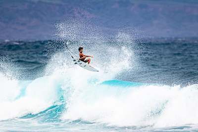 Eli Hanneman performs a backhand aerial while surfing at home in Maui