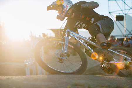 Tomas Slavik rides around a pump track in a full face helmet and knee pads.