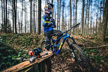 Martin Maes in a forest sat on his bike next to a drone.