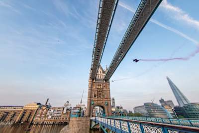 Red Bull wingsuiter flying through Tower Bridge in London.