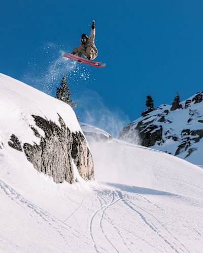 In Tahoe, California, Brock Crouch catches big air while filming for Red Bull Media House and Burton Snowboards' 2024 PAVED project, showcasing epic snowboarding action amid snowy cliffs