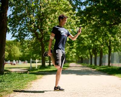 Philipp Hansa s'étire l'avant de la cuisse pendant la course sur l'application de la Wings For Life World Run.