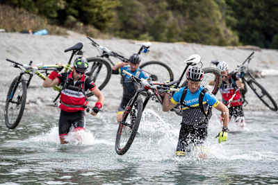 Competitors carry their bikes through water during adventure race.
