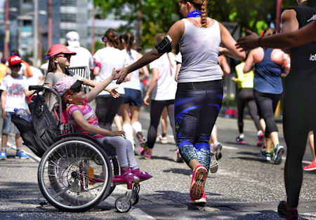 Runner high fives little girl in wheelchair