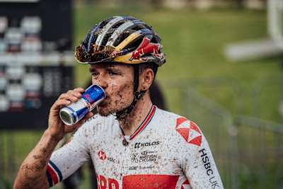 Le cycliste Tom Pidcock boit un Red Bull pendant un entrainement de VTT.